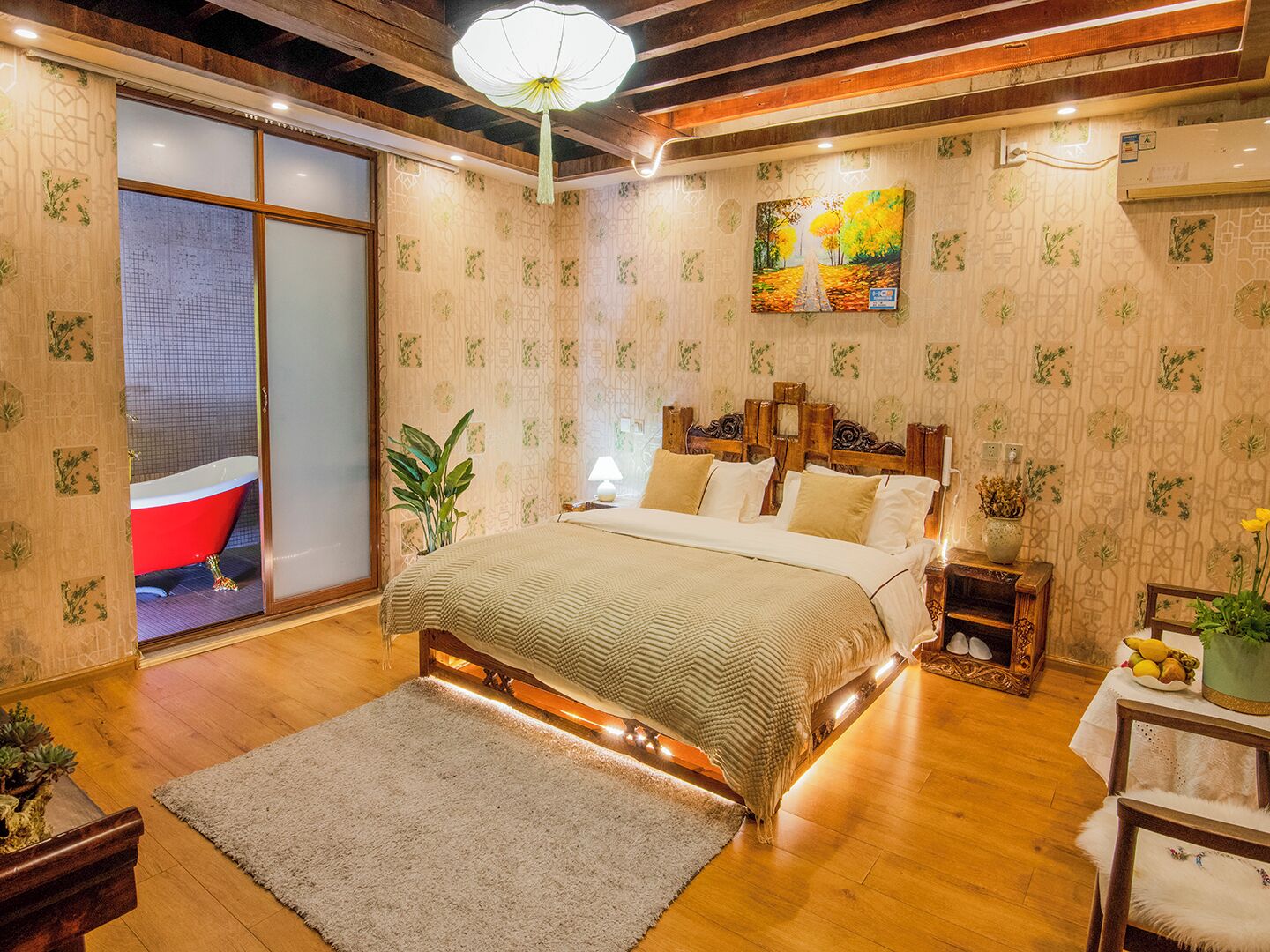A bedroom with a large bed, a red bathtub, and a wooden ceiling.