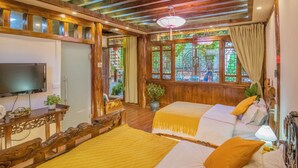 A room with two beds, a TV, wooden furniture, and a view of greenery outside. - Erquan Inn Ancient city (Lijiang)
