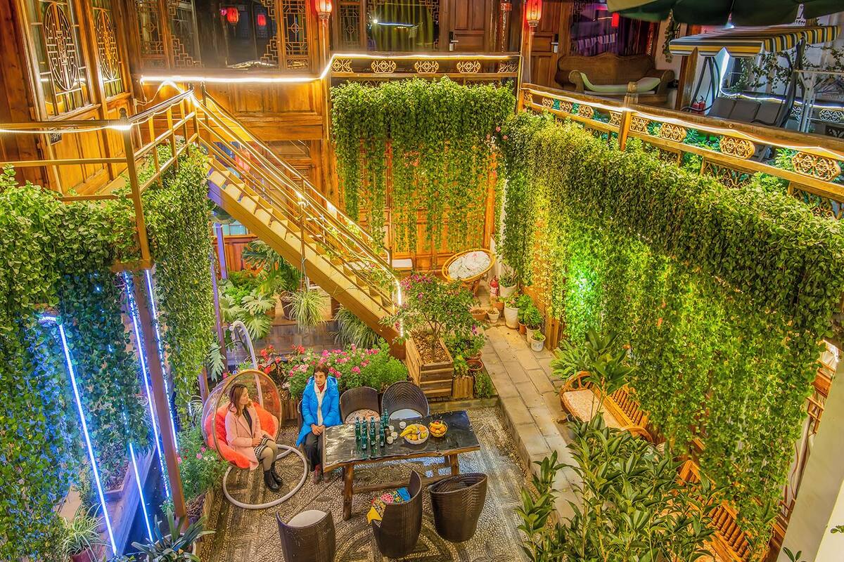 An indoor atrium with a central staircase surrounded by lush greenery and wooden railings.