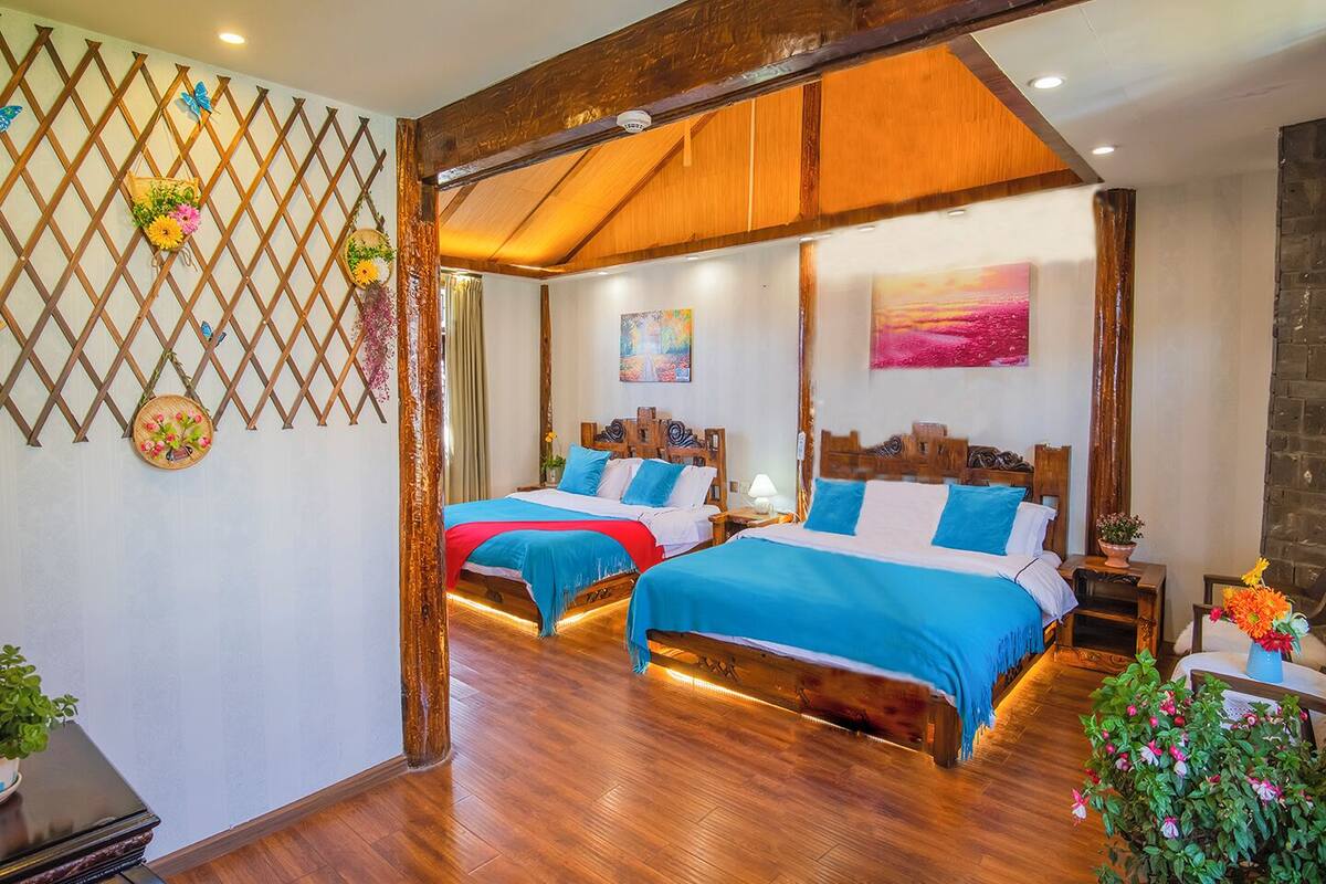 A hotel room with two beds, wooden flooring, a lattice wall, and a painting.