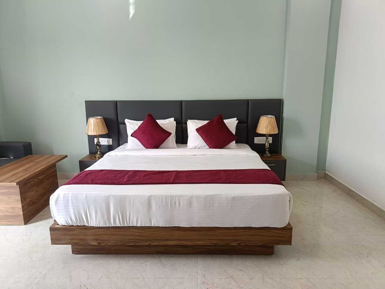 A neatly made bed with a wooden frame, two nightstands with lamps, and a wooden side table.