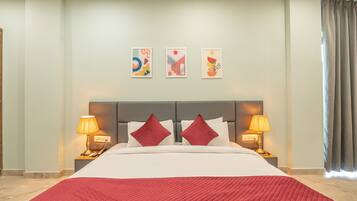 A hotel room with a large bed, two bedside lamps, a headboard, and three wall art pieces.