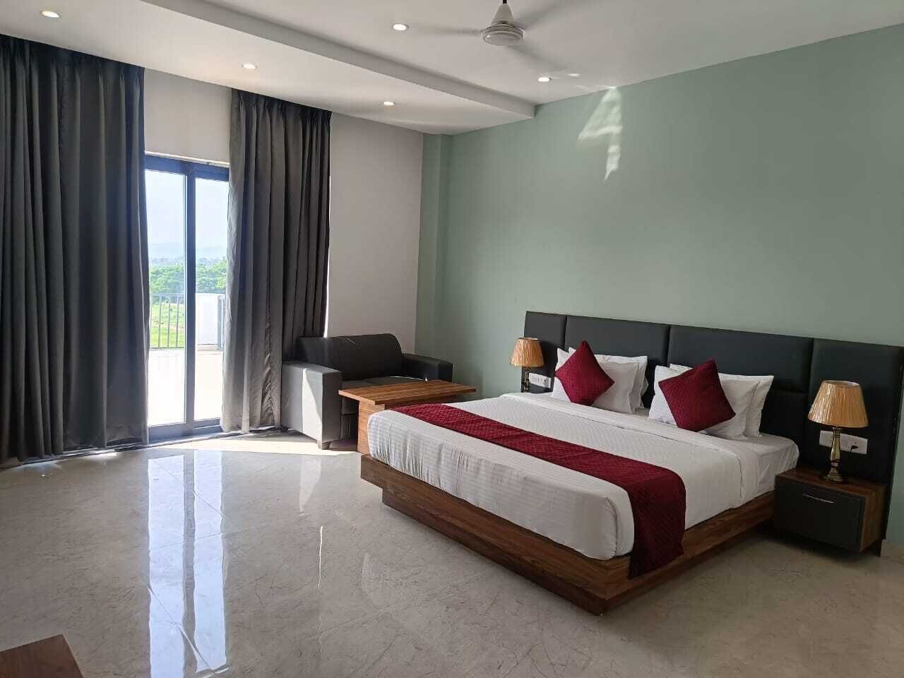 A modern hotel room with a large bed, a desk, and a view of the outdoors.