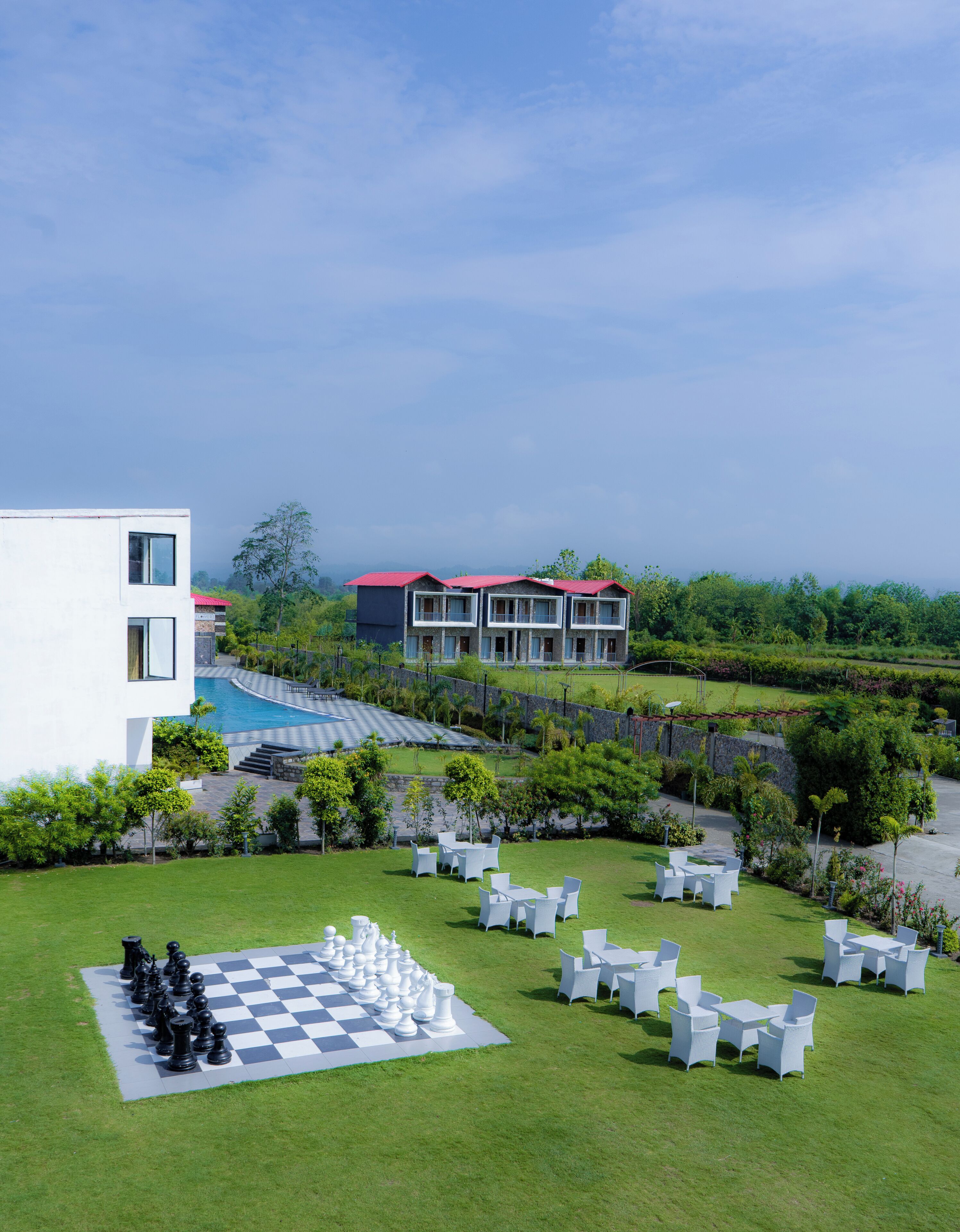 A modern building with a pool, outdoor seating, and a large chessboard.