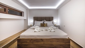 A modern bedroom with a wooden headboard, a large bed with white linens, and bedside lamps.