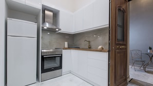 A modern kitchen with white cabinets, stainless steel appliances, and a wooden door.