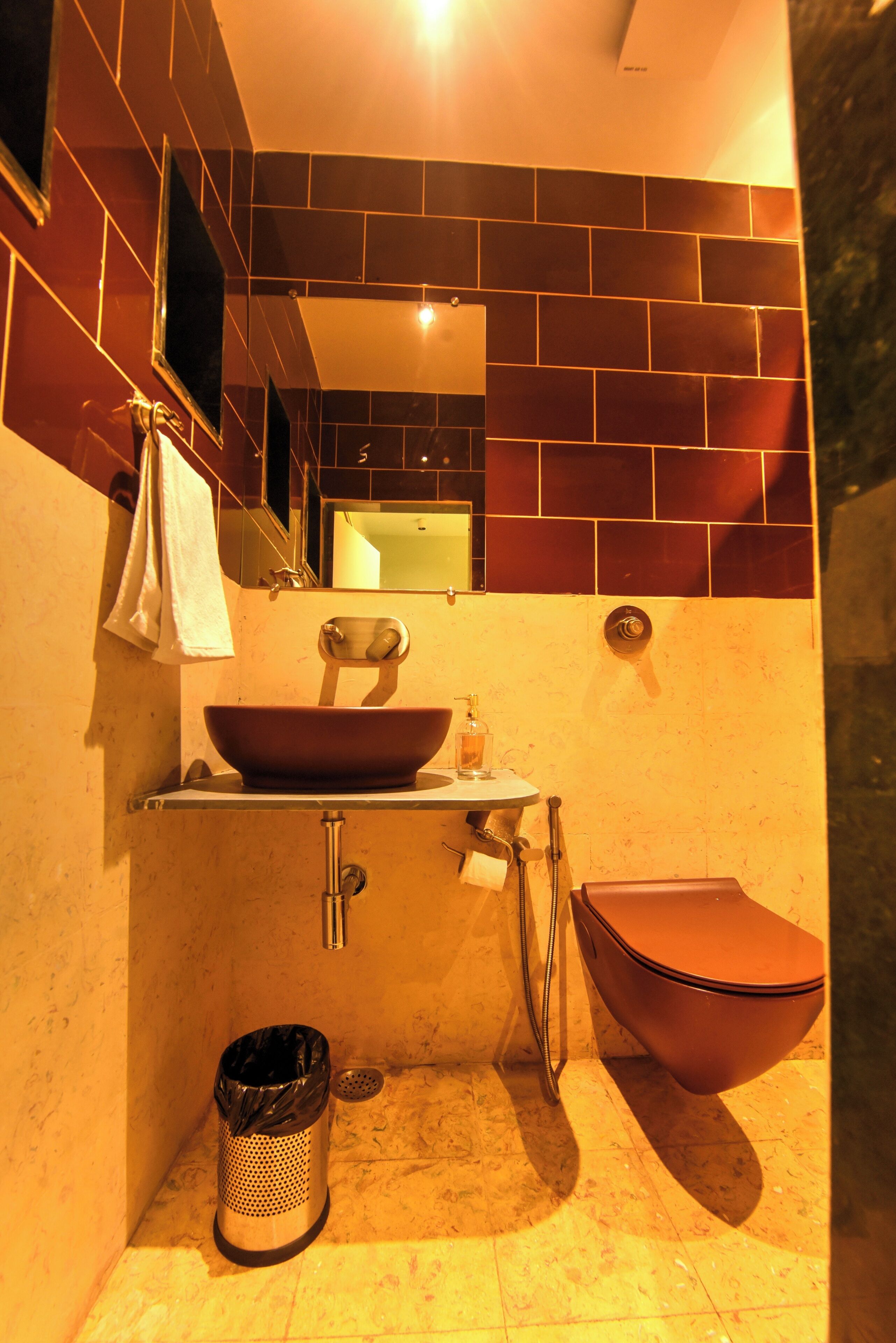 A bathroom with a large vessel sink, a toilet, and a mirror above the sink.
