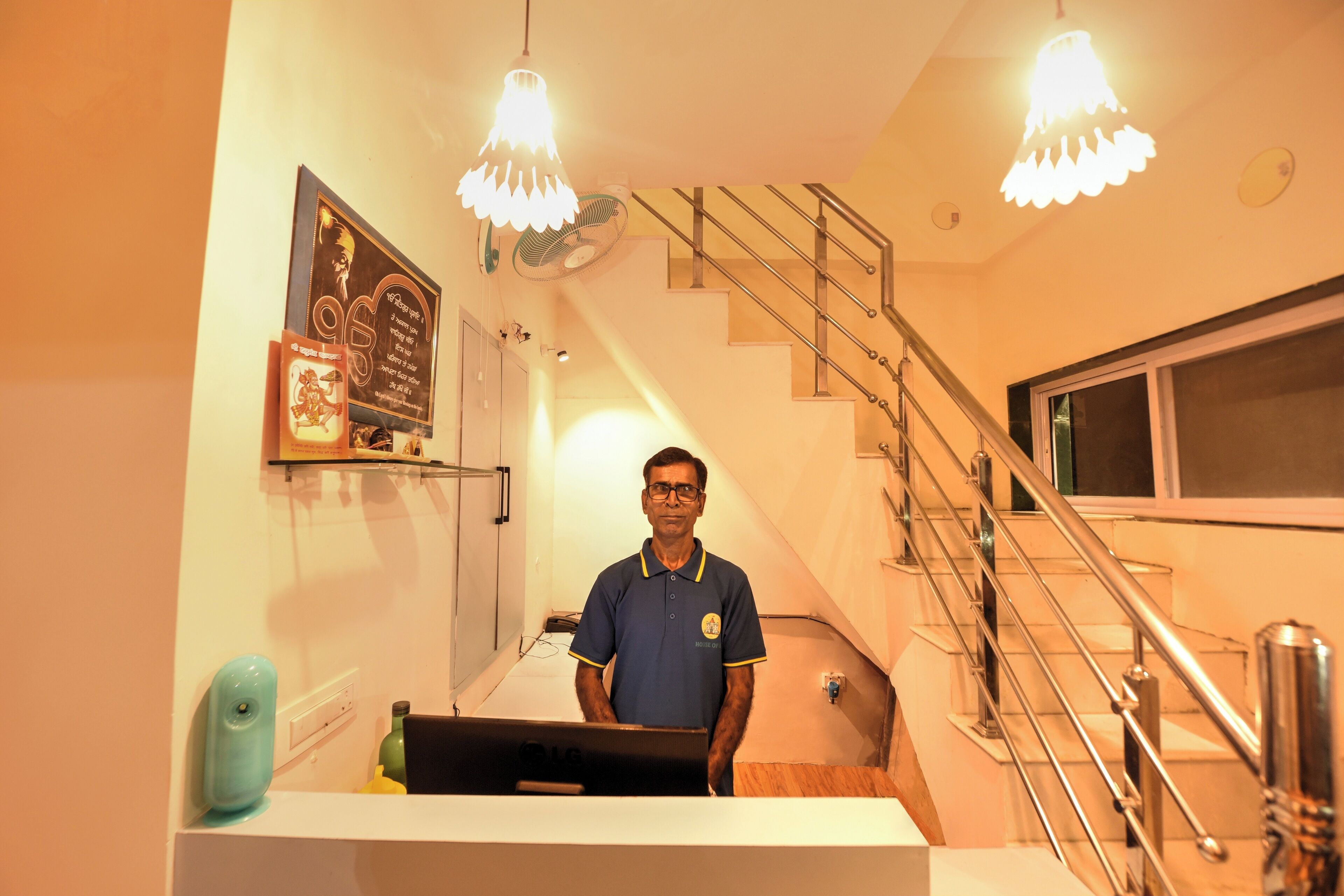 A man standing in a hotel lobby with a staircase and a framed picture on the wall.