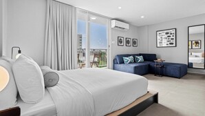 Une chambre d’hôtel moderne dotée d’un grand lit, d’un canapé, d’un balcon avec vue et d’un climatiseur fixé au mur.