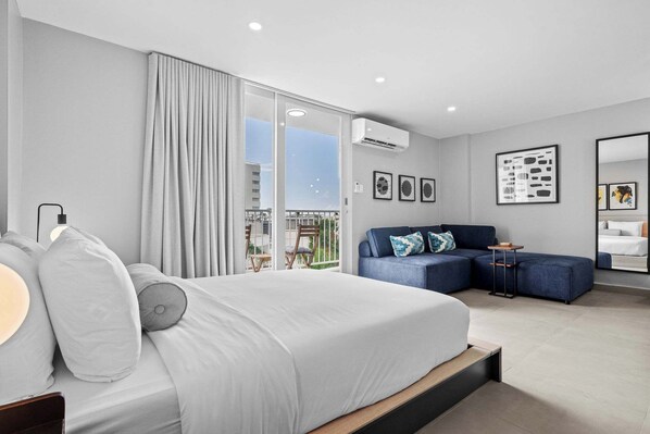 Une chambre d’hôtel moderne dotée d’un grand lit, d’un canapé, d’un balcon avec vue et d’un climatiseur fixé au mur.