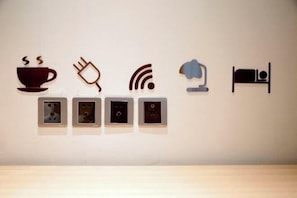 Wall-mounted icons representing amenities: a coffee cup, plug, Wi-Fi, lamp, and bed. - IU Hotel (Ancient City of Zhengding Rongguofu) (Zhengding)