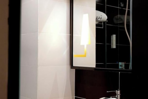 A bathroom with white tiles, a mirror, a towel rack, and a shower area. - IU Hotel (Ancient City of Zhengding Rongguofu) (Zhengding)