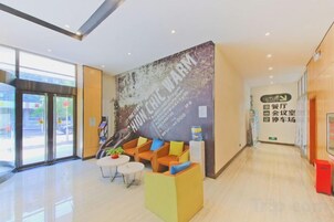 A hotel lobby with a reception desk, seating area, and a large wall with text.