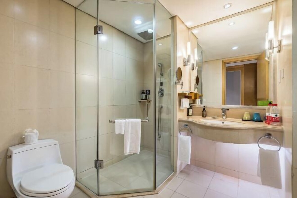 A modern bathroom with a glass-enclosed shower, a toilet, a sink with a mirror, and a towel rack.