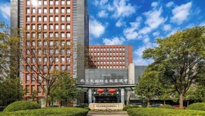 Un edificio moderno con una entrada destacada, grandes ventanales y un cielo despejado.