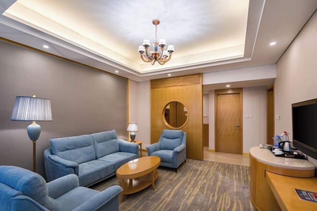 A hotel room with a sofa set, a round coffee table, a TV, and a reception desk.