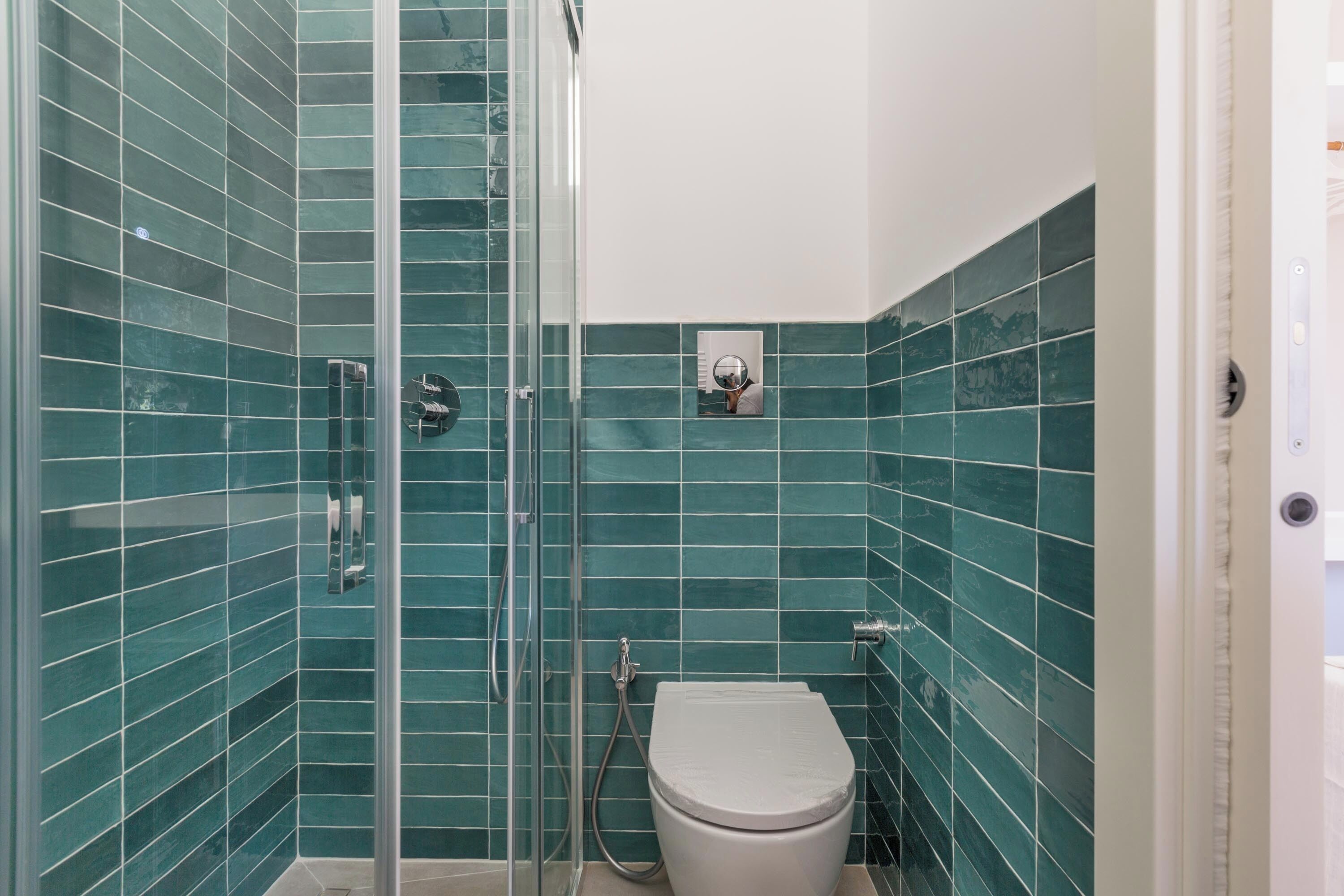 A bathroom with a glass-enclosed shower, a toilet, and a sink.