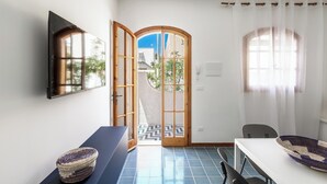 A room with a large wooden door, a small table with a woven basket, a white table, and a chair. - 4019 Villetta Biancamare by Barbarhouse (Carovigno)