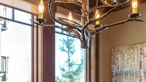 A wooden table with a brown paper bag with a tag on it, a chandelier, and a painting on the wall. - Close to Skiing and Winter Sports, Gas Log Fireplace, Mtn View, Gated Resort, In (Boone)