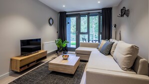 Uma sala de estar moderna com um sofá, uma mesa de centro, uma TV e uma planta.