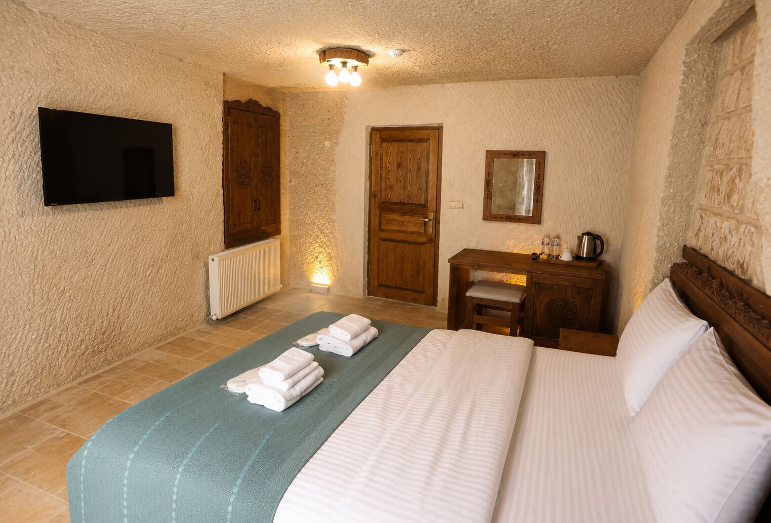 Una habitación de hotel con cama, escritorio, espejo y televisión.