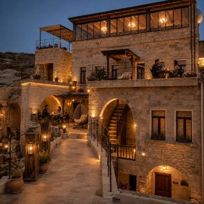 Ein Gebäude aus Stein mit einem zentralen Innenhof, einer Treppe und einem Essbereich mit Tischen und Stühlen.
