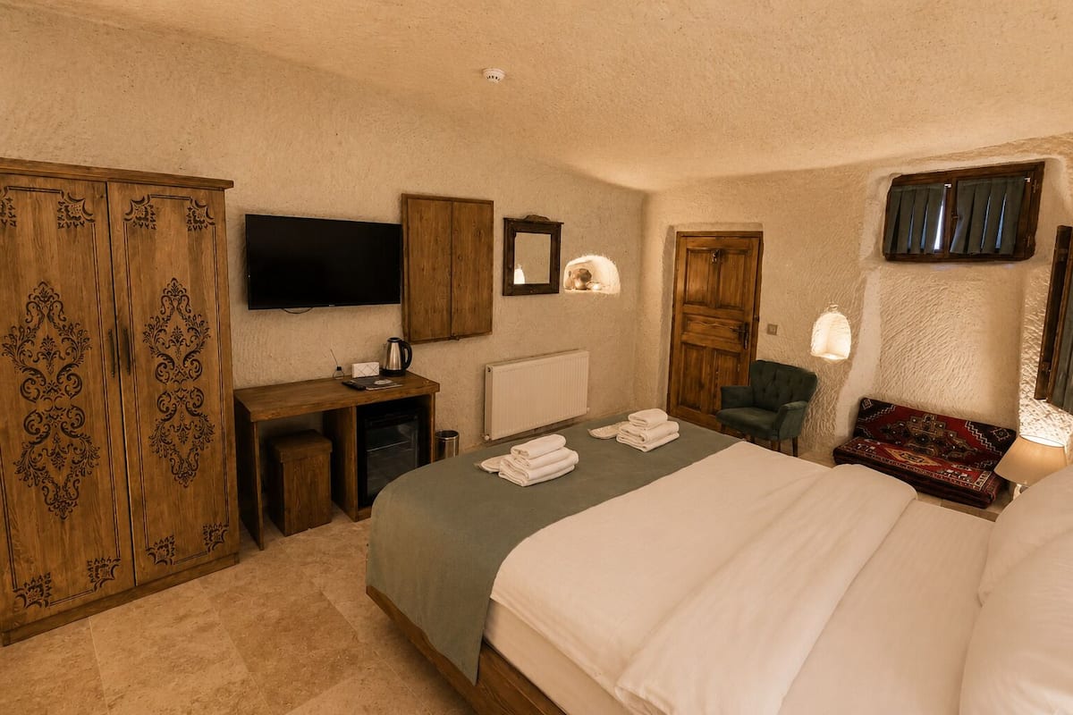 A bedroom with a bed, a desk, a television, a wardrobe, and a chair.