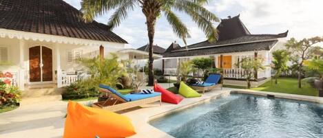 A swimming pool with lounge chairs and a palm tree.