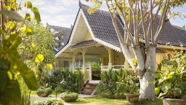 A traditional building with a tiled roof, surrounded by lush greenery and a pathway leading to the entrance. - Puri Tempo Doeloe Boutique Hotel (Bali)