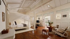 A spacious room with a bed, a desk, and a chair. - Puri Tempo Doeloe Boutique Hotel (Bali)