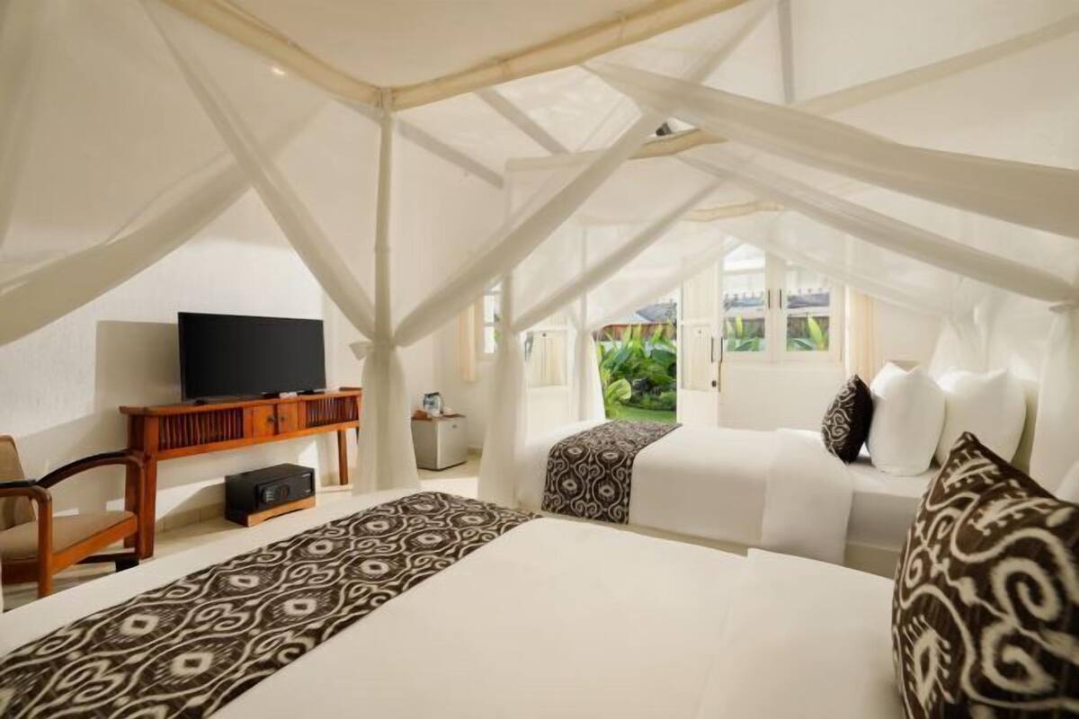 Een kamer met een bed, een televisie en een raam met uitzicht op groen.