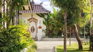 A traditional building with a tiled roof, surrounded by lush greenery and a pathway leading to the entrance. - Puri Tempo Doeloe Boutique Hotel (Bali)