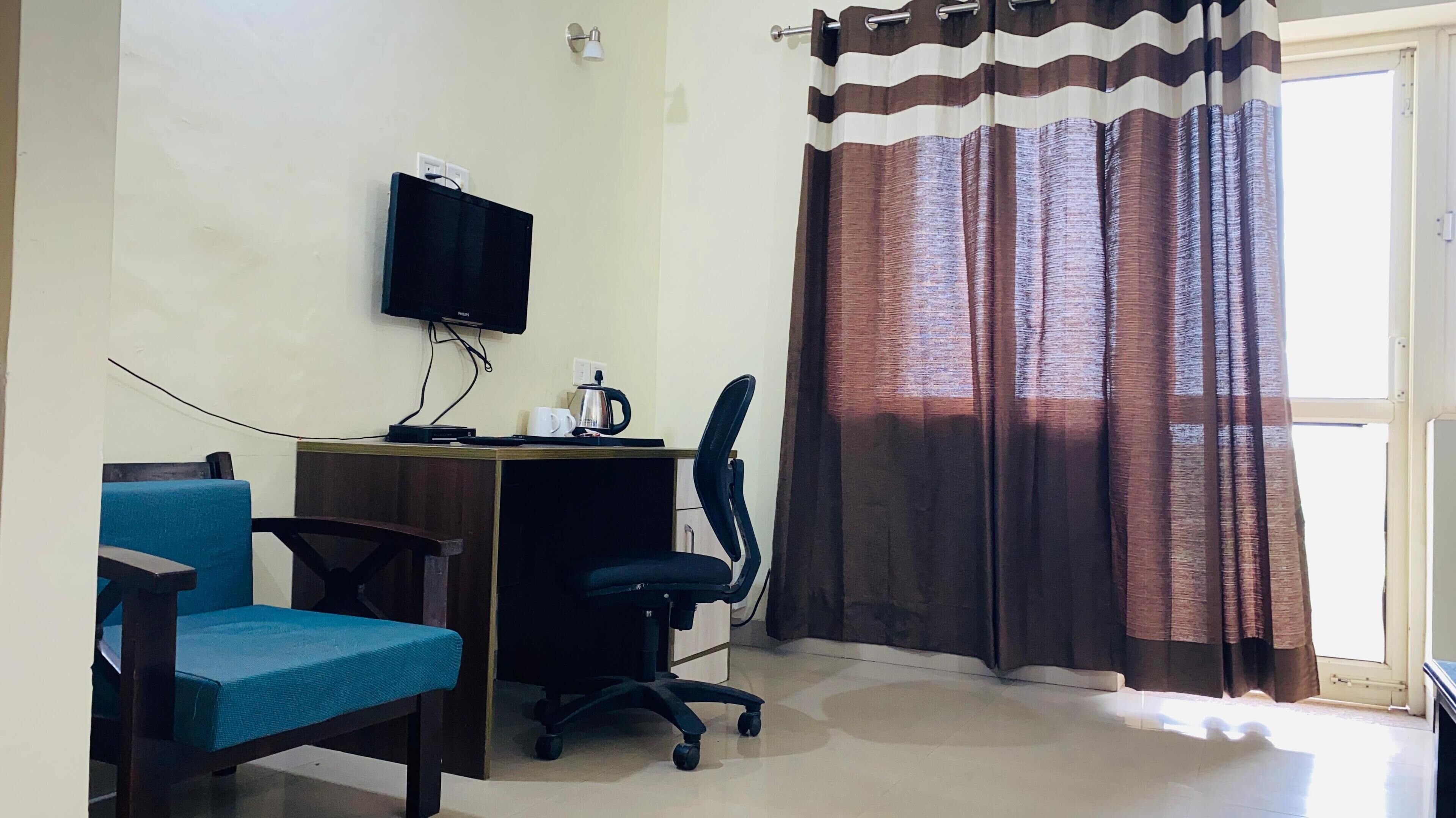 A small office space with a desk, chair, and a television mounted on the wall.