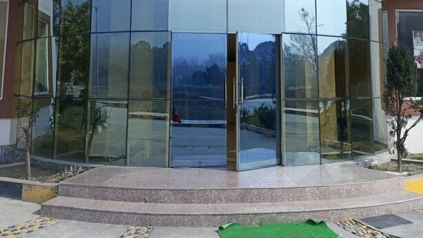 A modern building with a curved glass facade and a central entrance. - LivBox Rudrapur (Kichha)