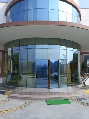 A modern building with a curved glass facade and a central entrance. - LivBox Rudrapur (Kichha)