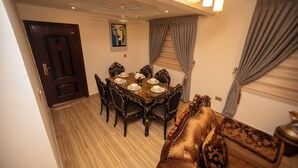 A dining area with a round table set for six, surrounded by ornate chairs. - Lily Of De Valley Residence (Kumasi)