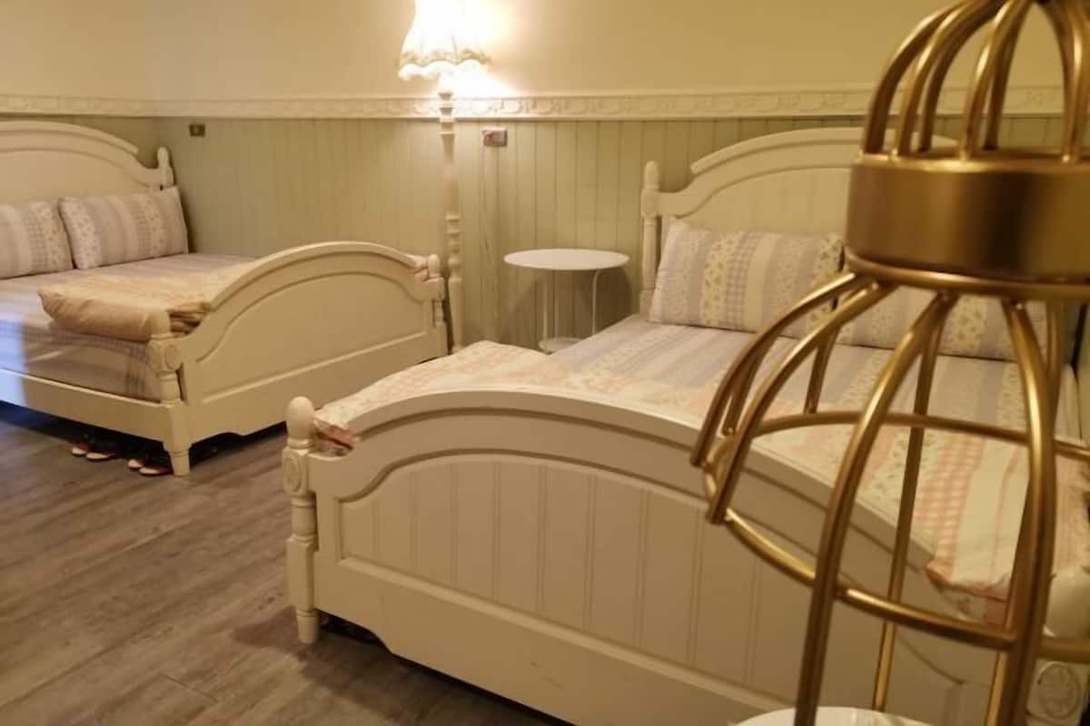 Un dormitorio con dos camas, una mesita redonda y una lámpara decorativa.