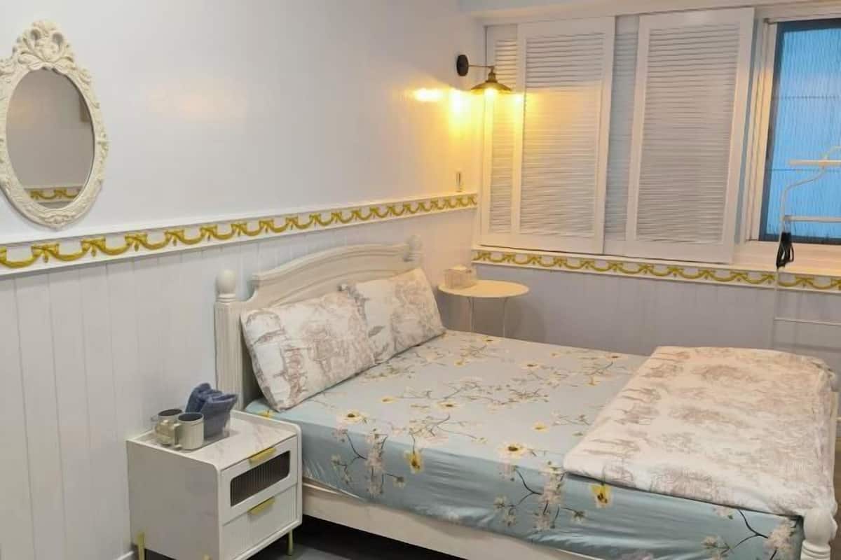 Un dormitorio con cama, mesita de noche y espejo.