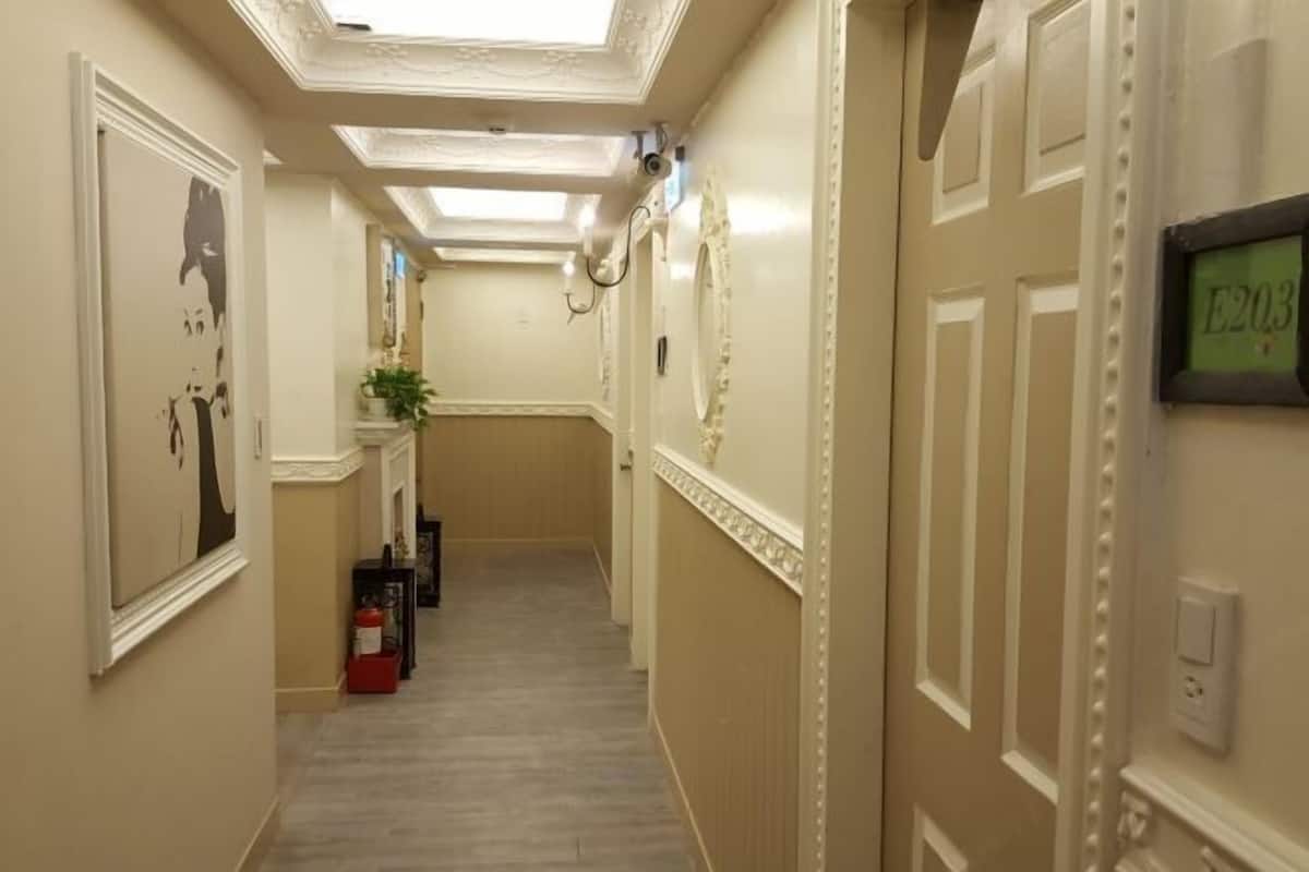 Un pasillo con paredes color crema, piso de madera y techo con tragaluces.