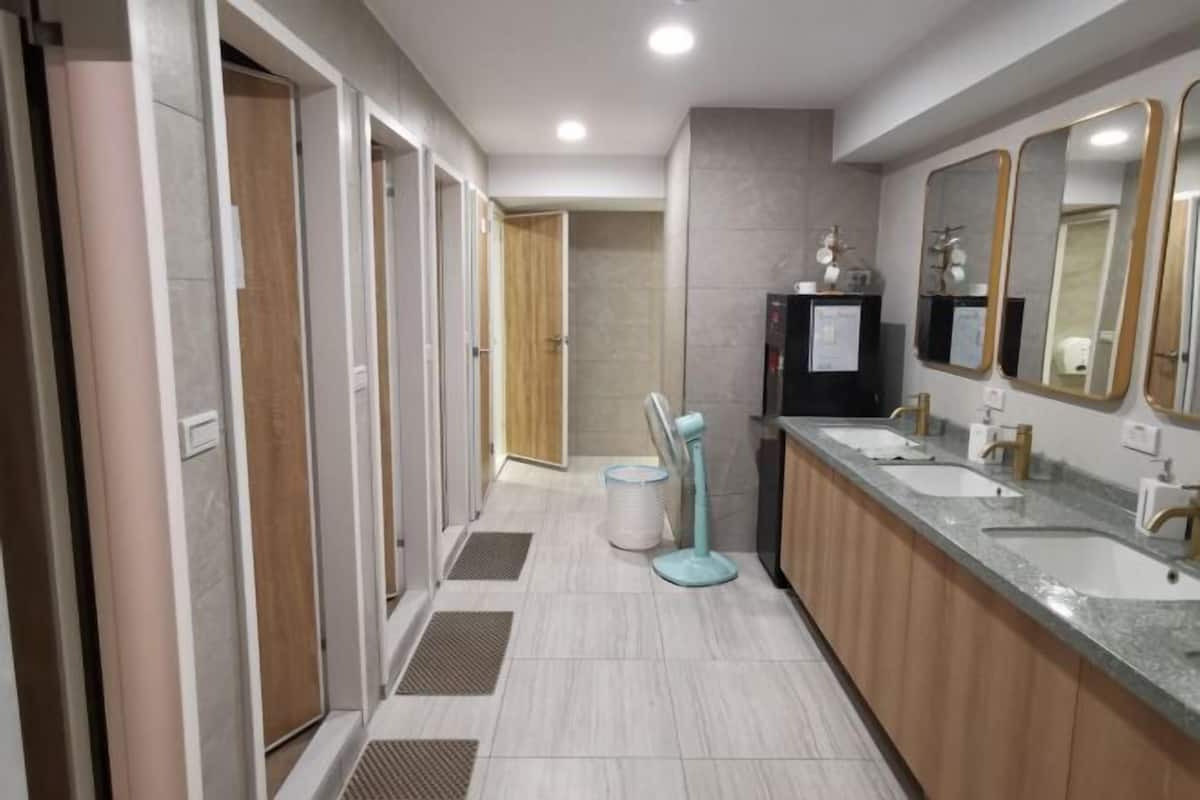 Un baño moderno con tres lavamanos, un tocador y un espejo.