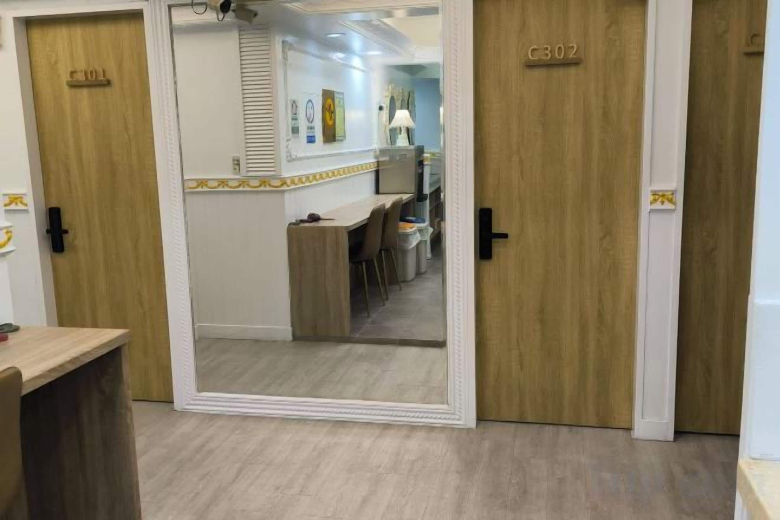Quarto de hotel com porta de madeira, espelho e vista para a recepção.