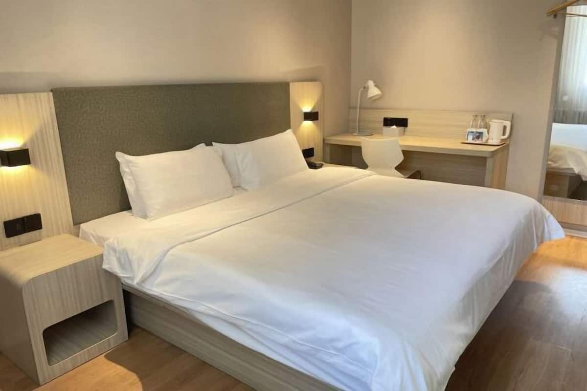 Une chambre d’hôtel avec un grand lit, des tables de chevet, un bureau et un miroir.
