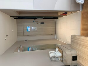 A compact kitchenette with a built-in stove, a small sink, and a storage cabinet. - Hanting Hotel (Zhengzhou)