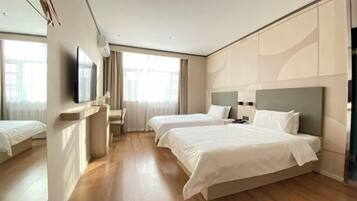 A hotel room with two beds, a TV, a desk, and a window with curtains.