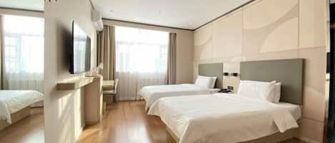 A hotel room with two beds, a TV, a desk, and a window with curtains.