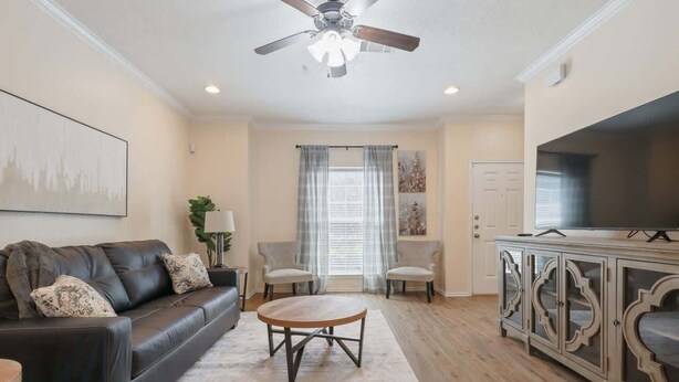 A living room with a sofa, chairs, a coffee table, a TV, and a cabinet. - Convenient Condo - 2BR 2 BA - Walk to Tech (Lubbock)