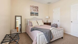 A bedroom with a bed, a chair, a nightstand, and a door. - Convenient Condo - 2BR 2 BA - Walk to Tech (Lubbock)
