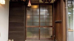 A traditional Japanese entrance with a sliding door, a small step leading up to the door, and a hanging lantern. - Rakumankan (Kyoto)