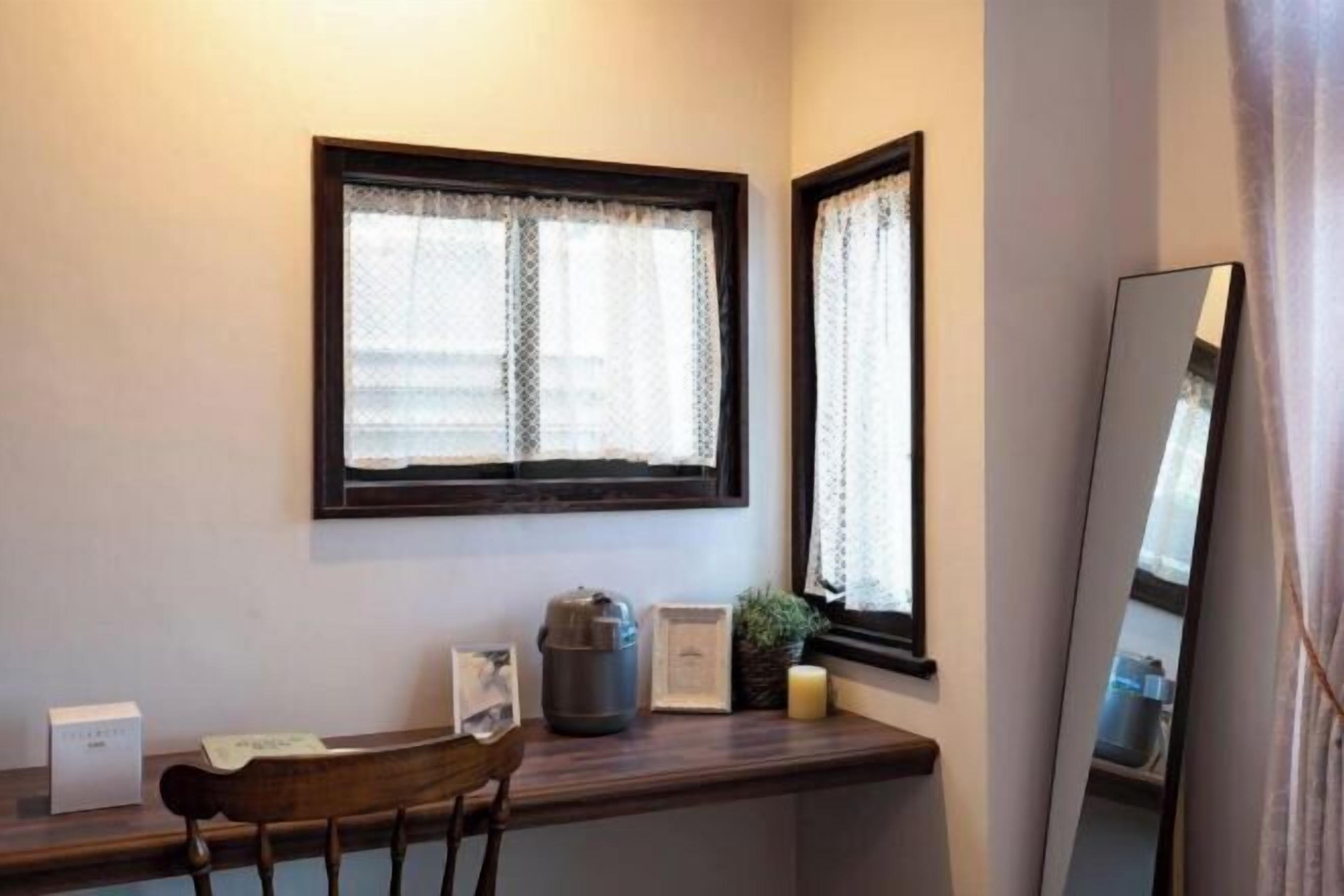 A small room with a window, a mirror, a desk, and a chair.