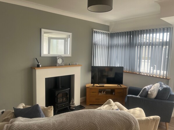 A living room with a fireplace, a television, and a comfortable seating area. - Seasideescape-2br-sleeps4-parking-petsok-fireplace (Bridlington)